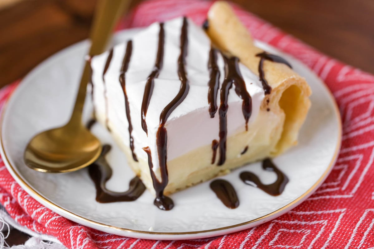 7月4日食谱——奶油泡芙bob综合手机客户蛋糕淋上巧克力，放在白色盘子上，用金勺子。