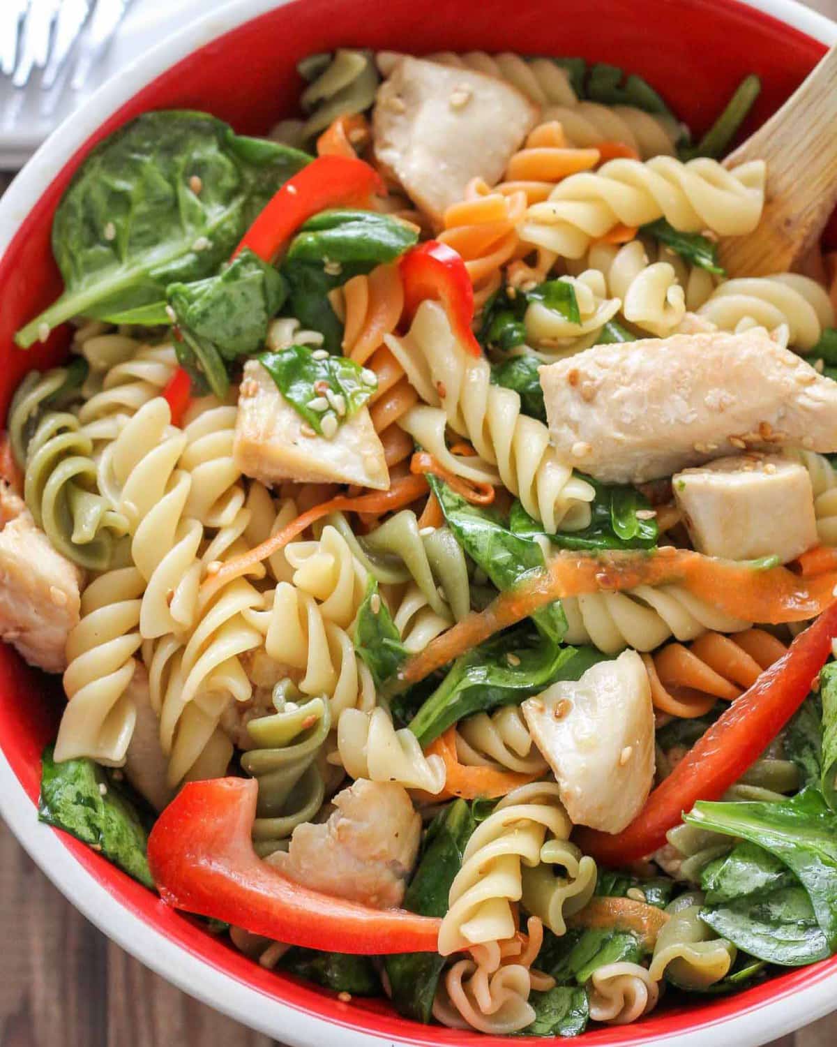 在白色和红色的碗里，浇上蔬菜的意大利面沙拉