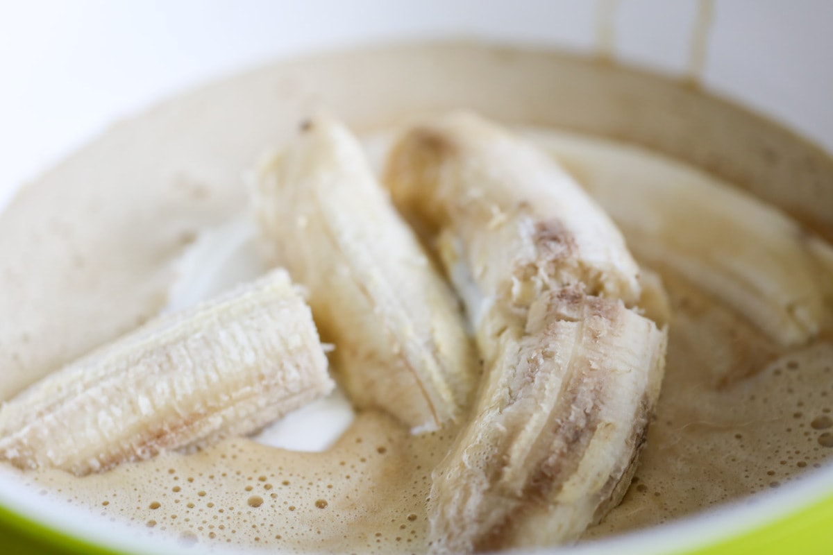 四根成熟的香蕉和面糊放在搅拌碗里。