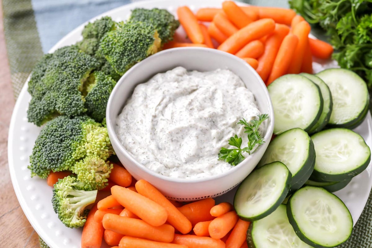 一碗白色的莳萝蔬菜蘸酱，周围是蔬菜——一个简单的开胃菜食谱。bob综合手机客户