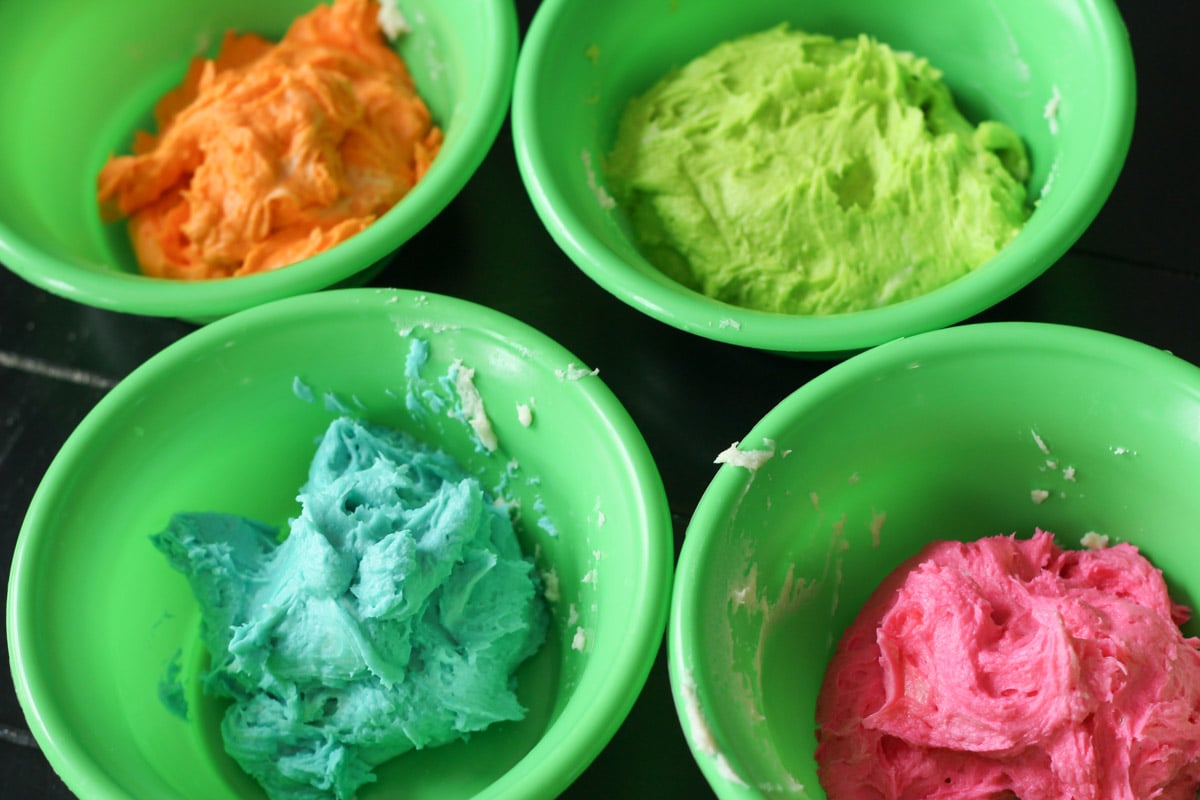 橙色，绿色，蓝色和粉色的饼干面团分别放在不同的碗里。
