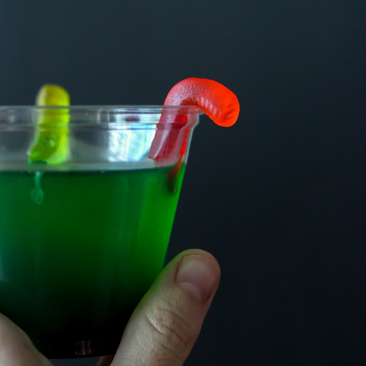 绿色果冻在一个透明的杯子和软糖蠕虫