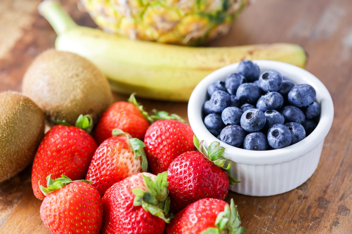 草莓、蓝莓、猕猴桃、香蕉和菠萝放在砧板上
