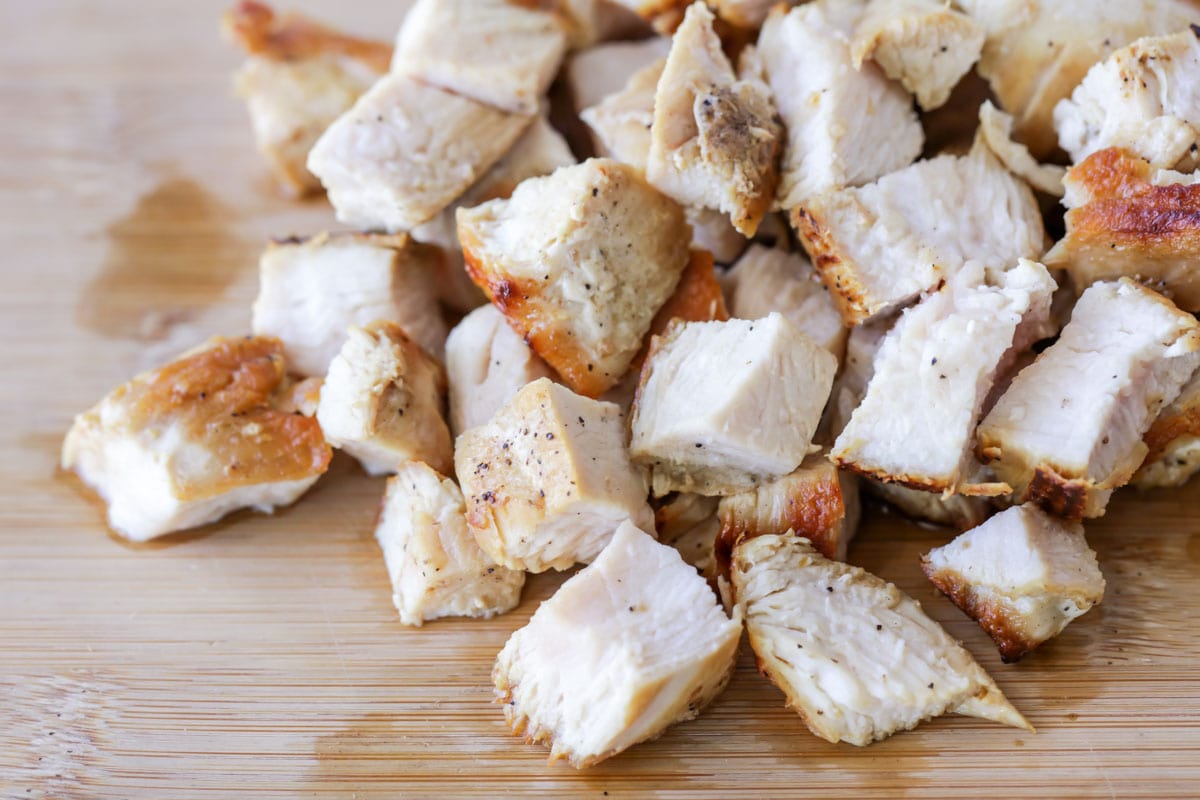 把煮好的鸡肉切成方块放在竹板上。