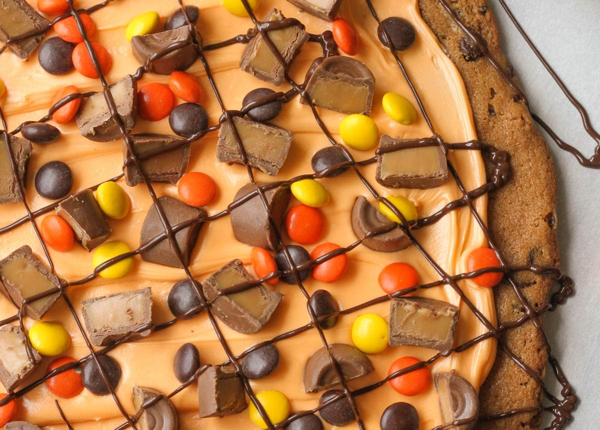 万圣节晚餐创意——橙色的万圣节饼干蛋糕，上面撒上糖果块和巧克力。