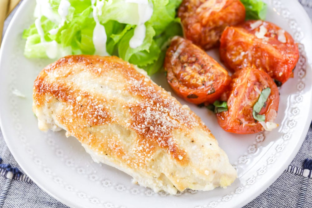 家庭晚餐的主意-梅奥帕尔玛鸡肉烤在盘子里烤西红柿和配沙拉。
