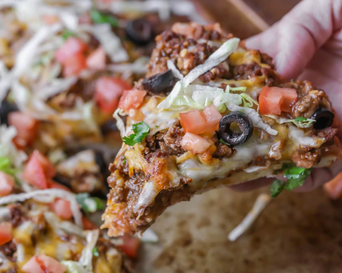 一只手拿着墨西哥玉米卷披萨