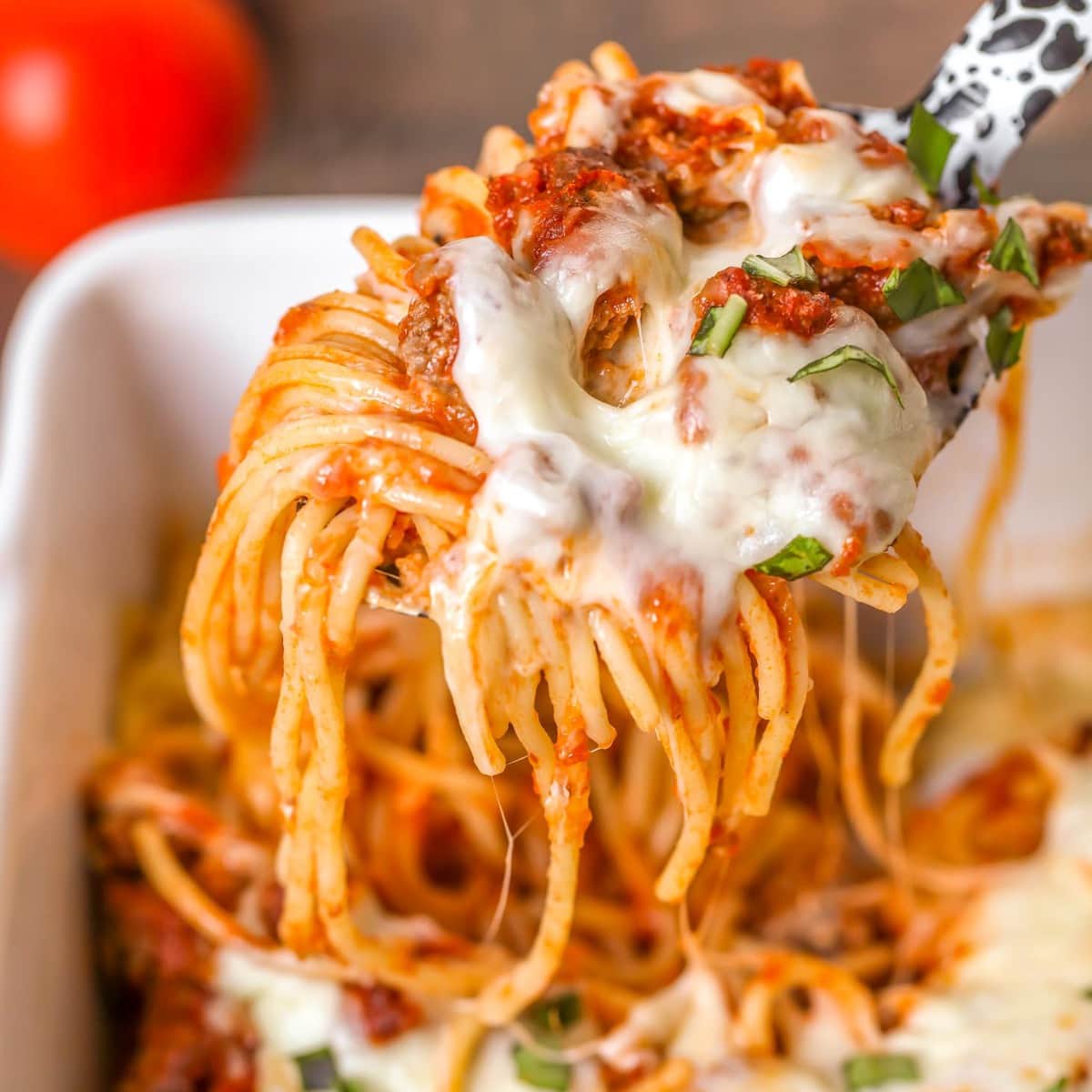 简单的意大利面食谱——bob综合手机客户用勺子舀一些烤意大利面。