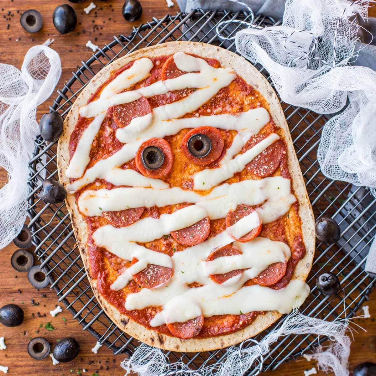 万圣节零食——万圣节大饼披萨上面有橄榄眼睛。