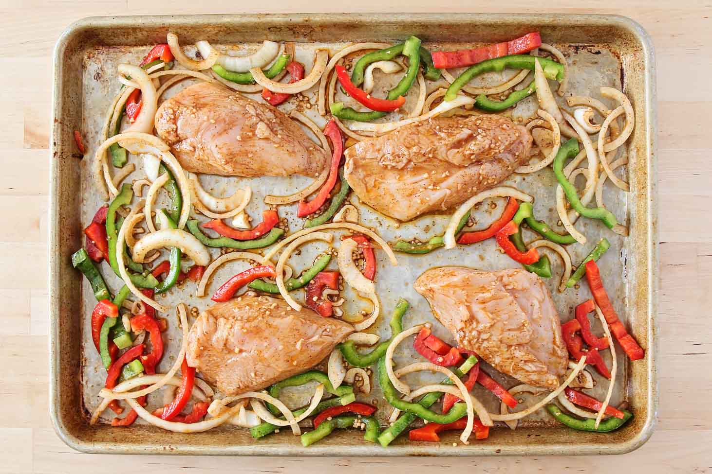 腌好的鸡肉和蔬菜片放在平底锅上。