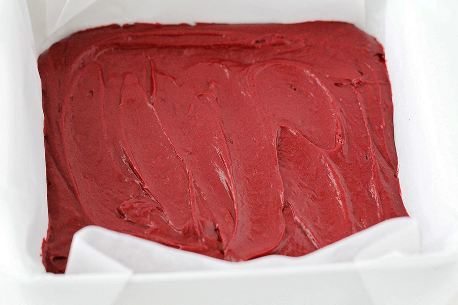 为烤盘里的红丝绒芝士布朗尼蛋糕涂面糊。