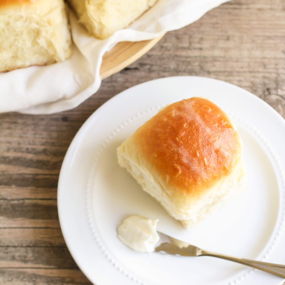 晚餐面包卷和饼干-酵母晚餐面包卷在一个白色的盘子上和一小块黄油。