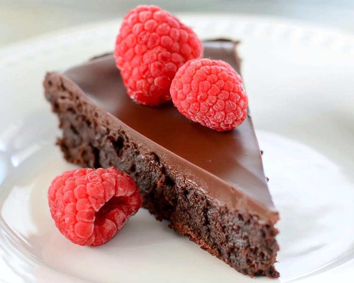 巧克力蛋糕食谱-无面粉巧克力蛋bob综合手机客户糕顶部新鲜覆盆子。