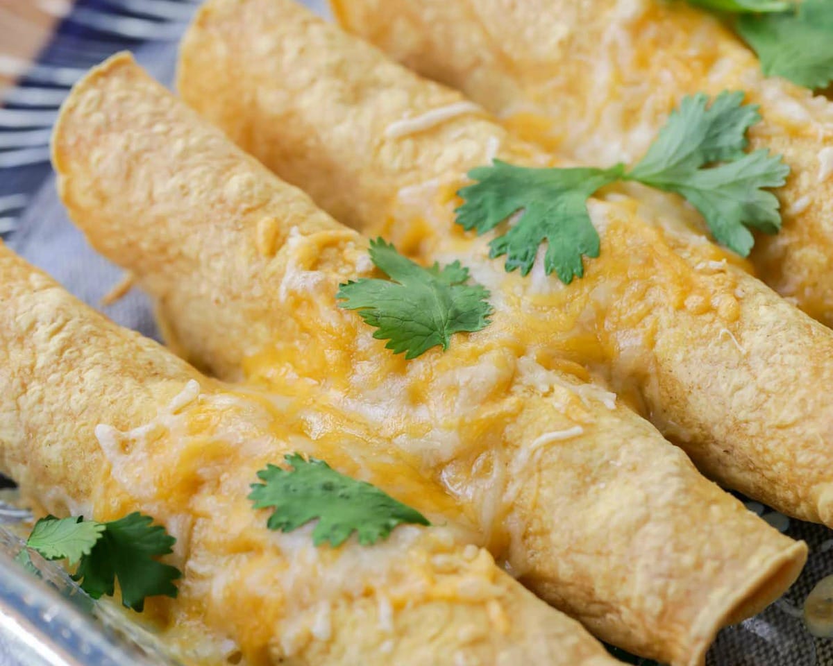 超级碗开胃菜——烤taquitos，上面有融化的奶酪和香菜叶。