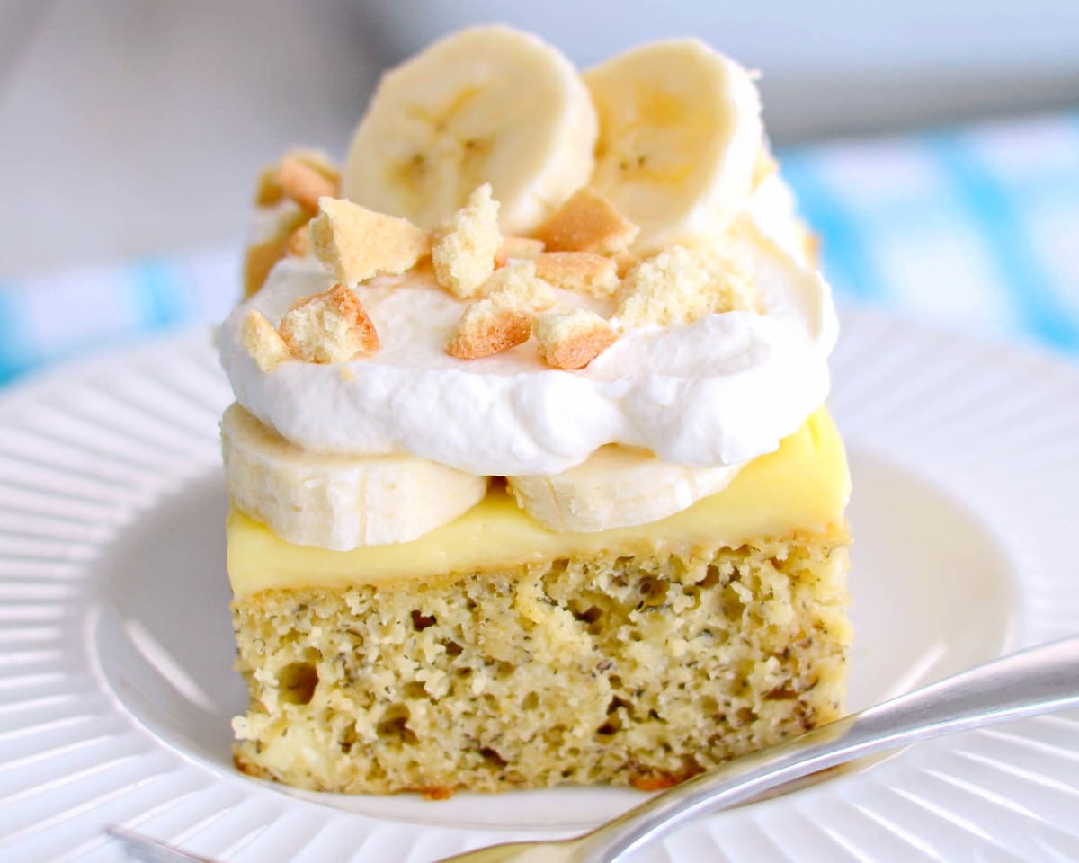 简单的蛋糕食谱-香蕉bob综合手机客户布丁戳蛋糕顶部新鲜的香蕉片和鲜奶油。