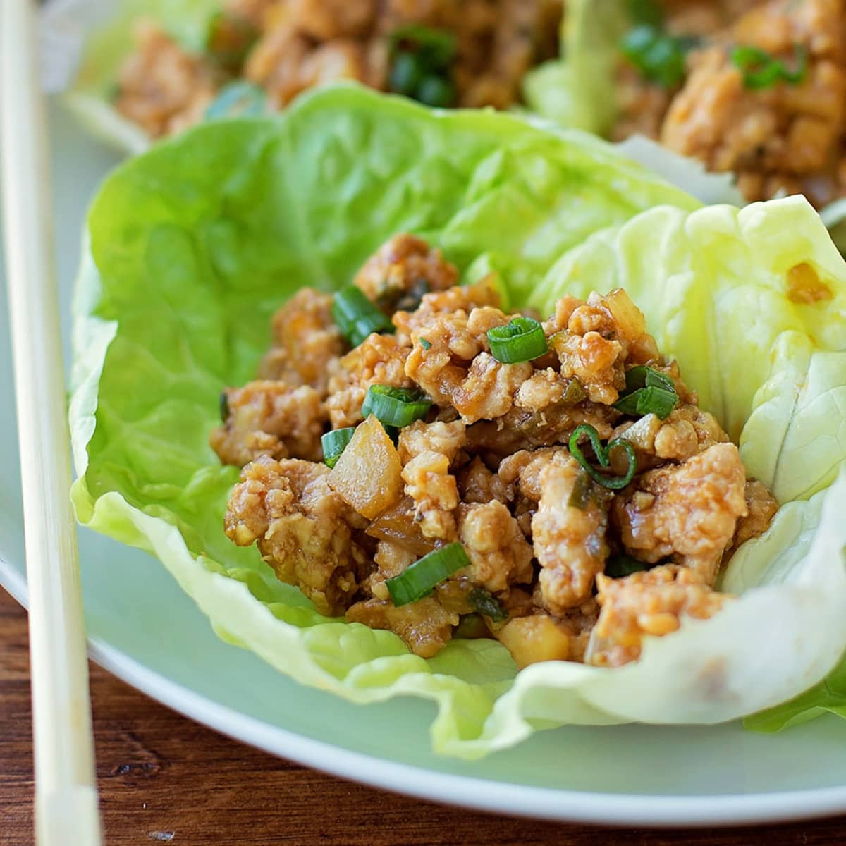 亚洲开胃菜——白色盘子上的鸡肉生菜卷。