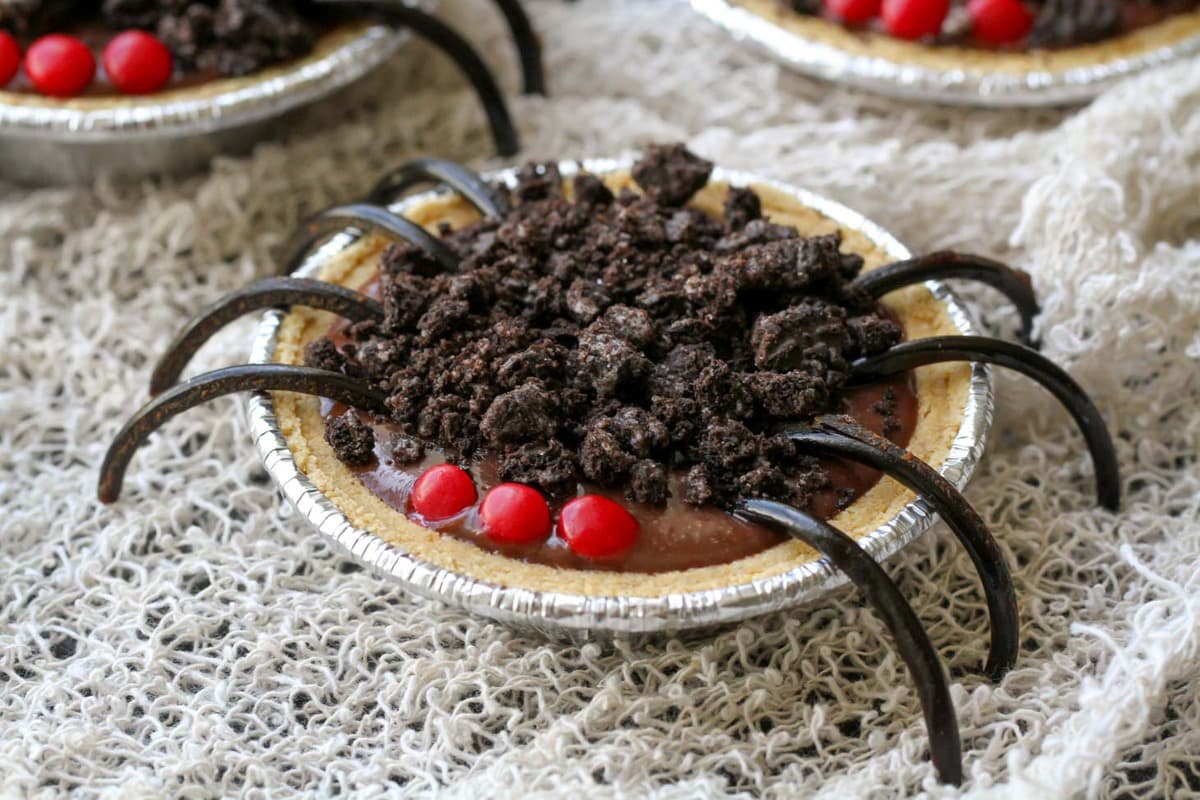 万圣节甜点——巧克力布丁派蜘蛛，上面有红色的糖果眼睛。