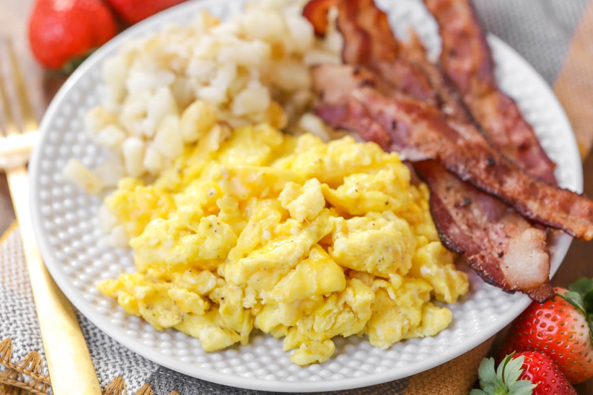 年代crambled eggs, bacon, and diced potatoes on a white plate.