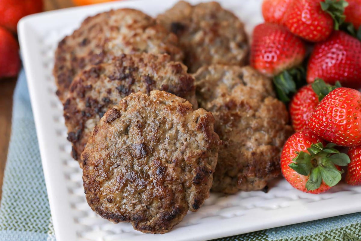 Easy Breakfast Ideas - sausage patties with a side of strawberries on a white plate.