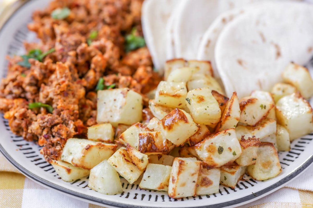 Easy Breakfast Ideas - diced potatoes with sides of chorizo and folded flour tortillas on a blue and white plate.