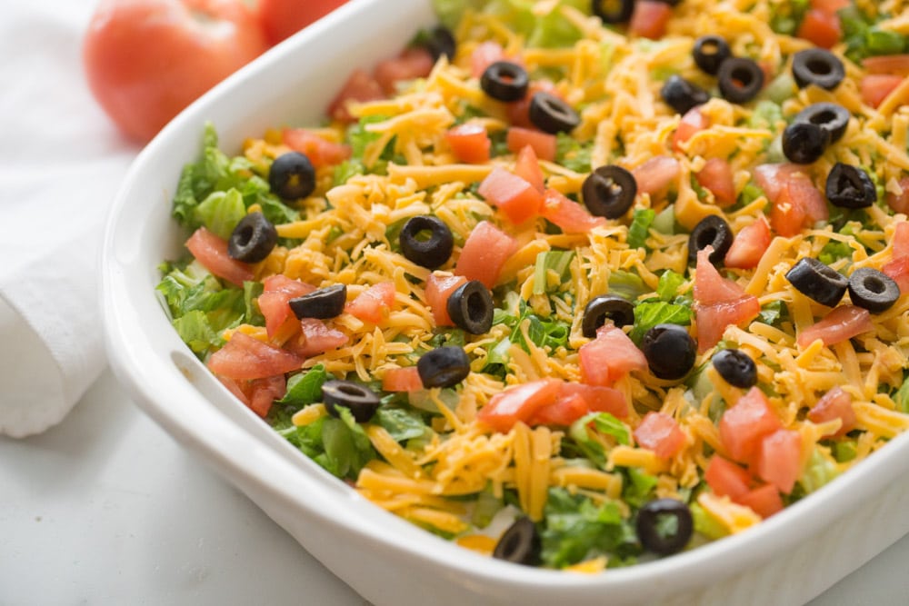 家庭晚餐建议-墨西哥玉米卷砂锅顶部有橄榄，西红柿和生菜。