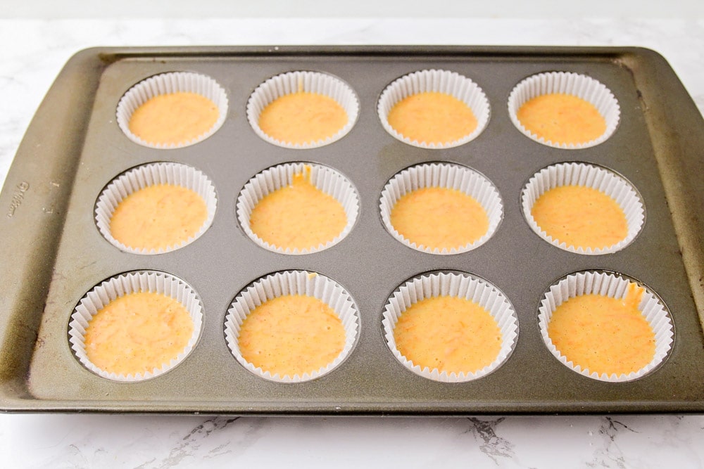 Carrot cake cupcake batter in a lined muffin tin.