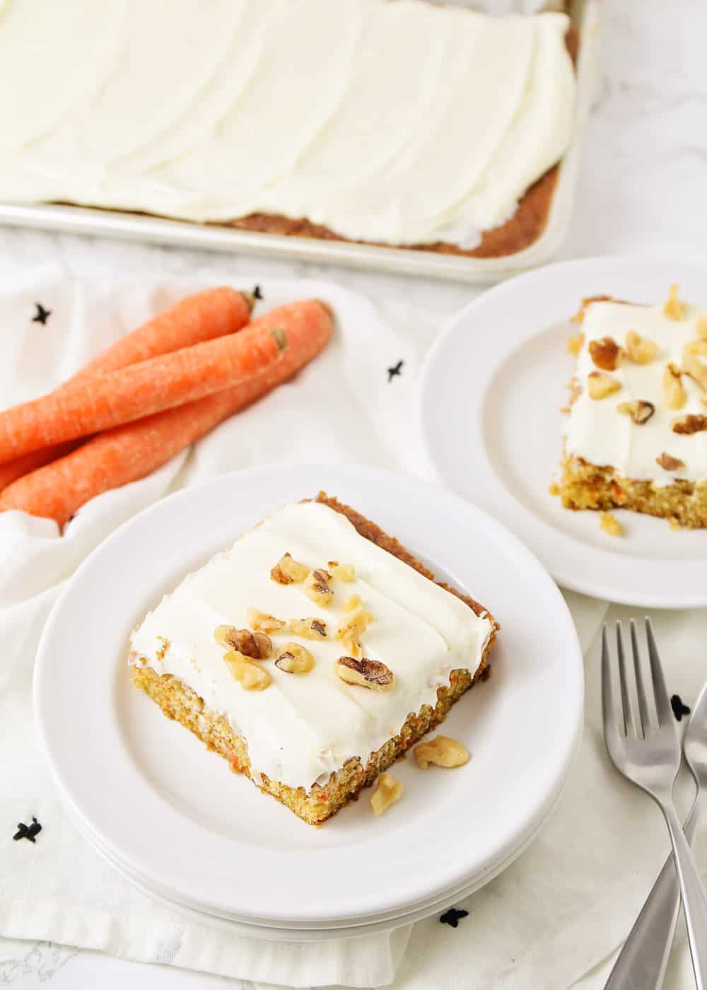 胡萝卜蛋糕食谱，切成薄片bob综合手机客户放在盘子上，上面撒上奶油奶酪糖霜和核桃。