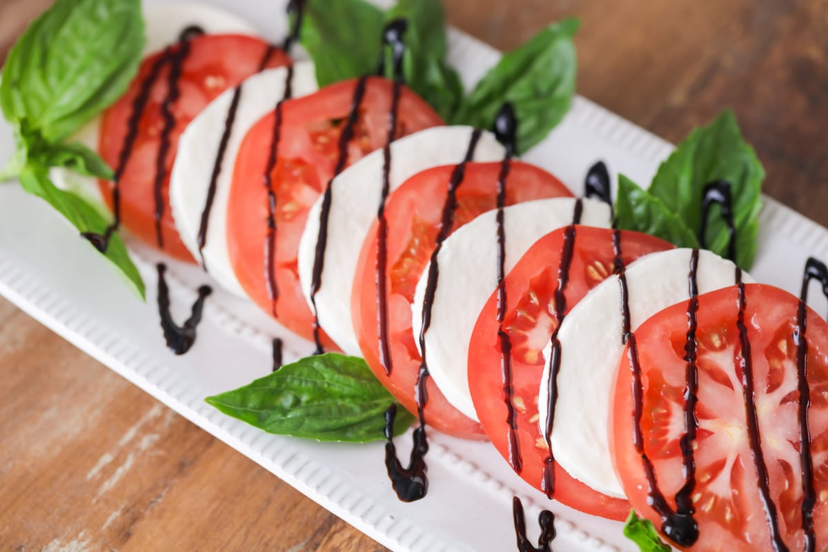 7月4日的配菜——番茄马苏里拉沙拉淋上香醋釉，放在白色浅盘上。