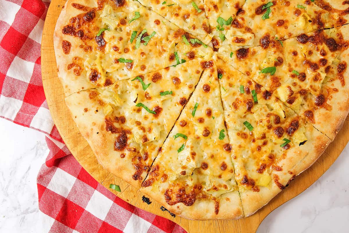 超级碗开胃菜-洋蓟披萨上的木制披萨皮。