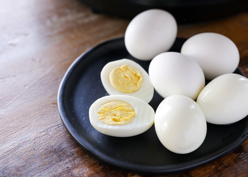 早餐鸡蛋食谱——煮熟的鸡蛋，bob综合手机客户一个鸡蛋切成两半，放在一个黑色的盘子里。