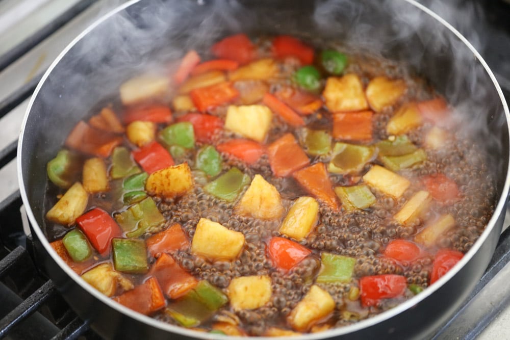 在炉子上的平底锅里，用亚洲酱汁炖煮蔬菜丁。