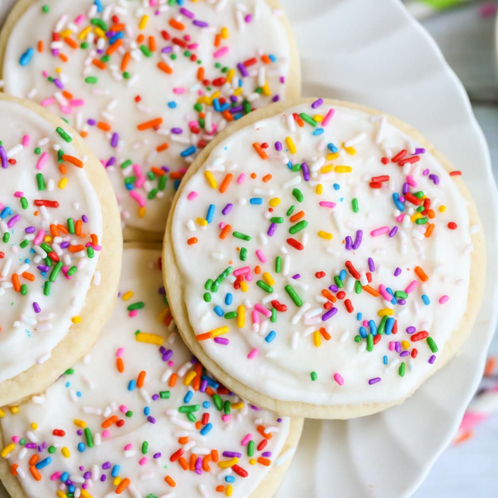 四块糖饼干放在一个白色的盘子里，上面有糖饼干的糖霜和彩色的糖屑。