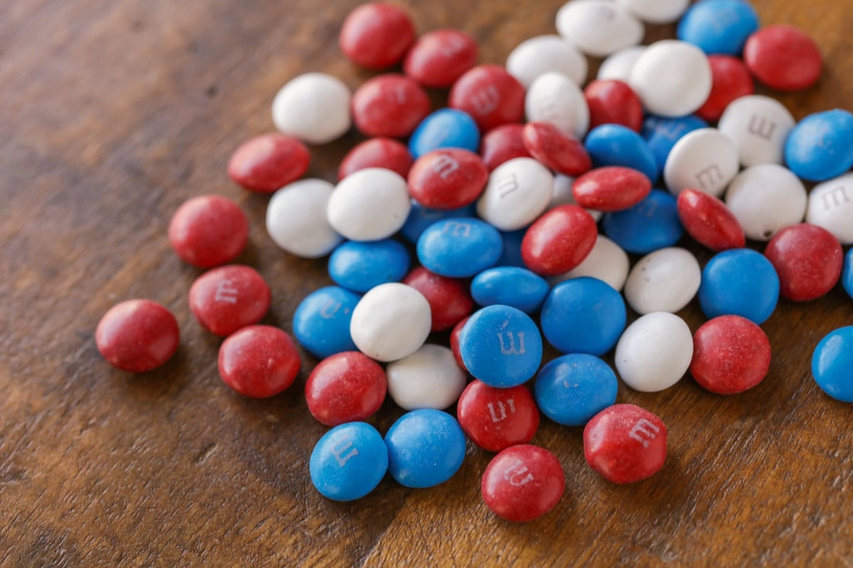 红色、白色和蓝色的m&m巧克力豆倒在木桌上。