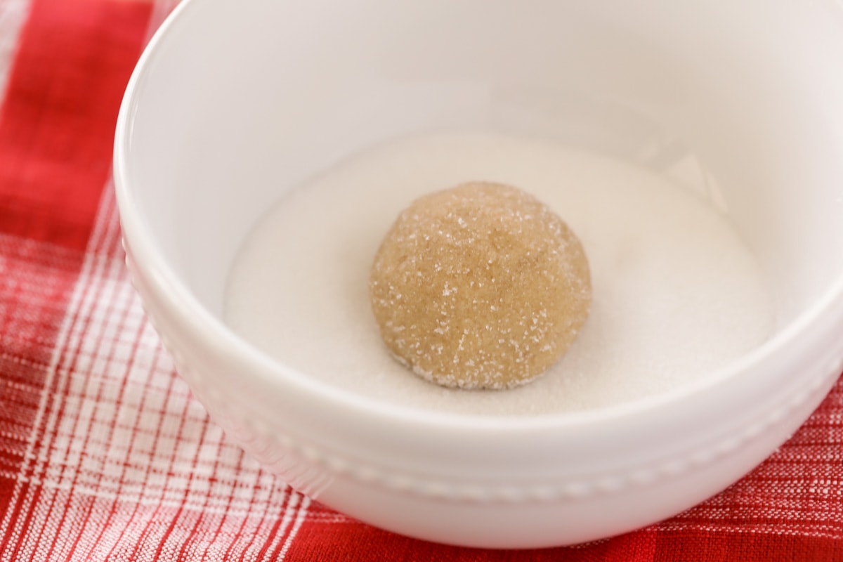 曲奇的原料红糖形成球状，置于盛有白糖的白碗中