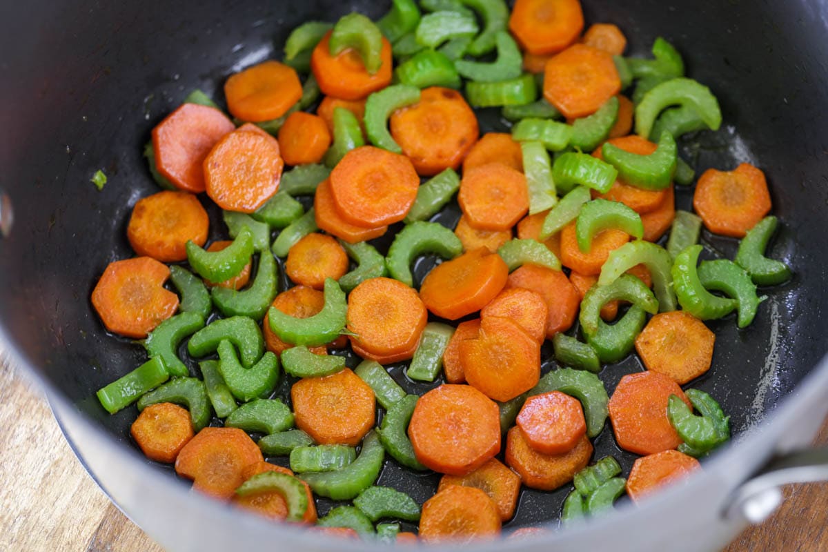 胡萝卜和芹菜sautéed在一个大锅里做健康的汤。