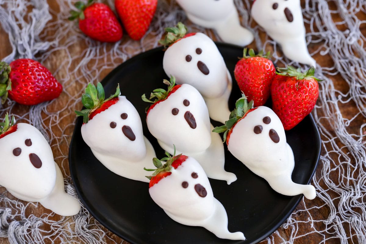 万圣节甜点——草莓幽灵装在黑色盘子里。