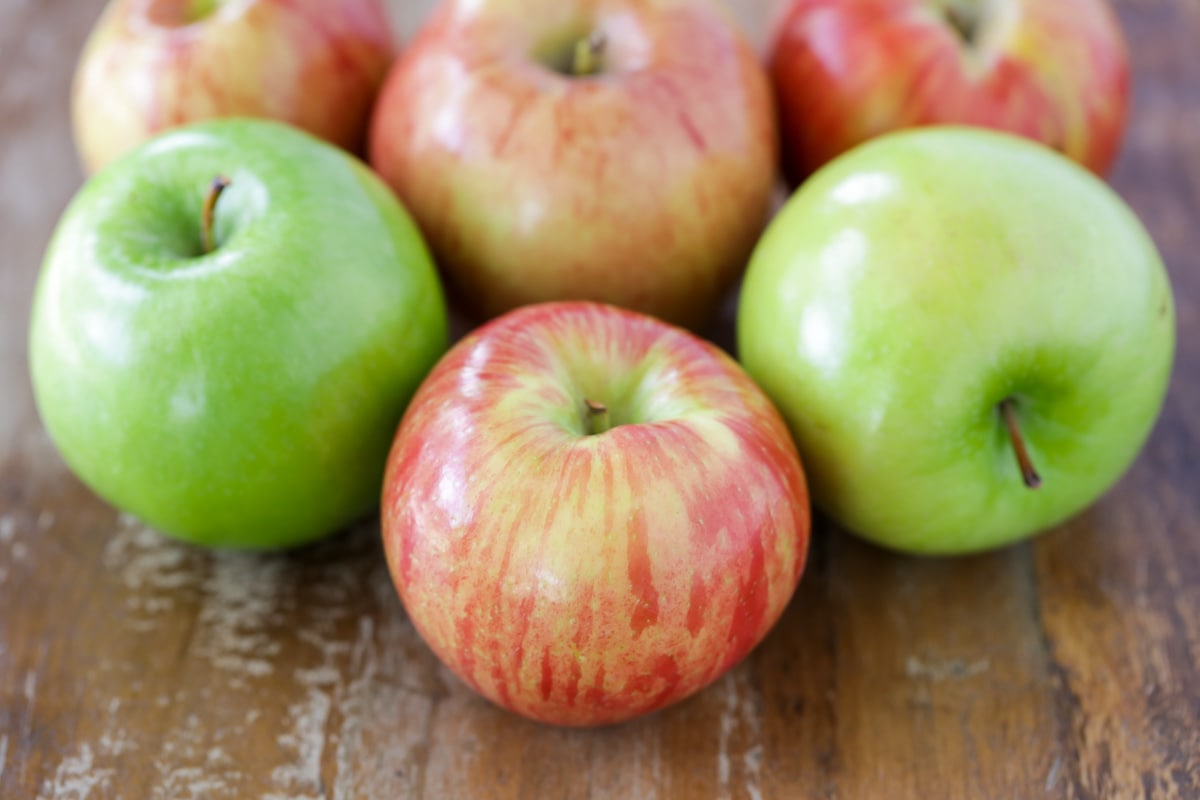 红色和绿色的苹果放在木头表面上。