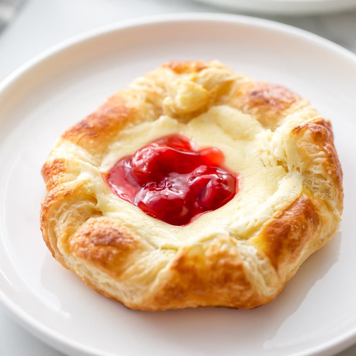 Easy Breakfast Ideas - a cherry Danish pastry on a white plate.