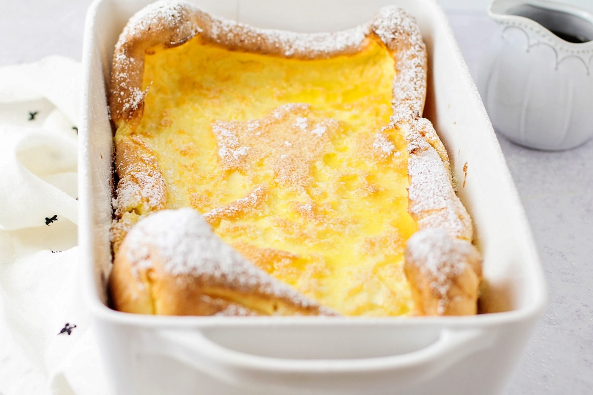 早餐鸡蛋食谱——德国煎饼上撒bob综合手机客户上糖粉，放在白色陶瓷烤盘中。