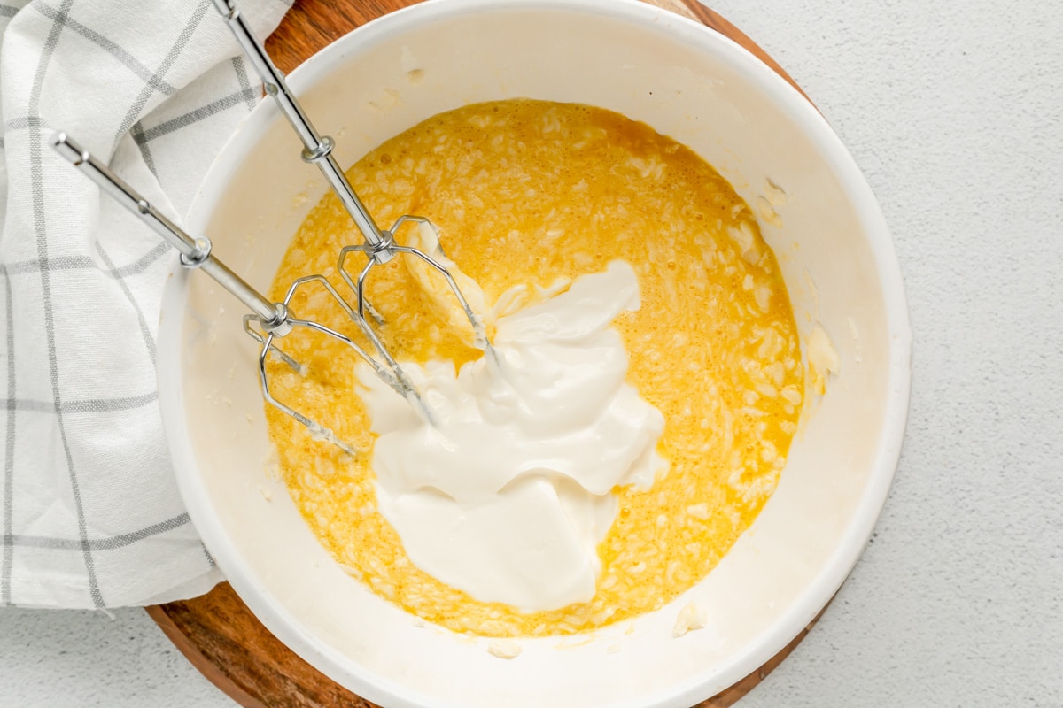 在一个白色的碗里搅拌玉米布丁的湿材料。
