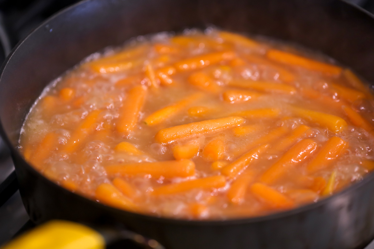小胡萝卜在水里煮，黄油和红糖变成上釉的胡萝卜。