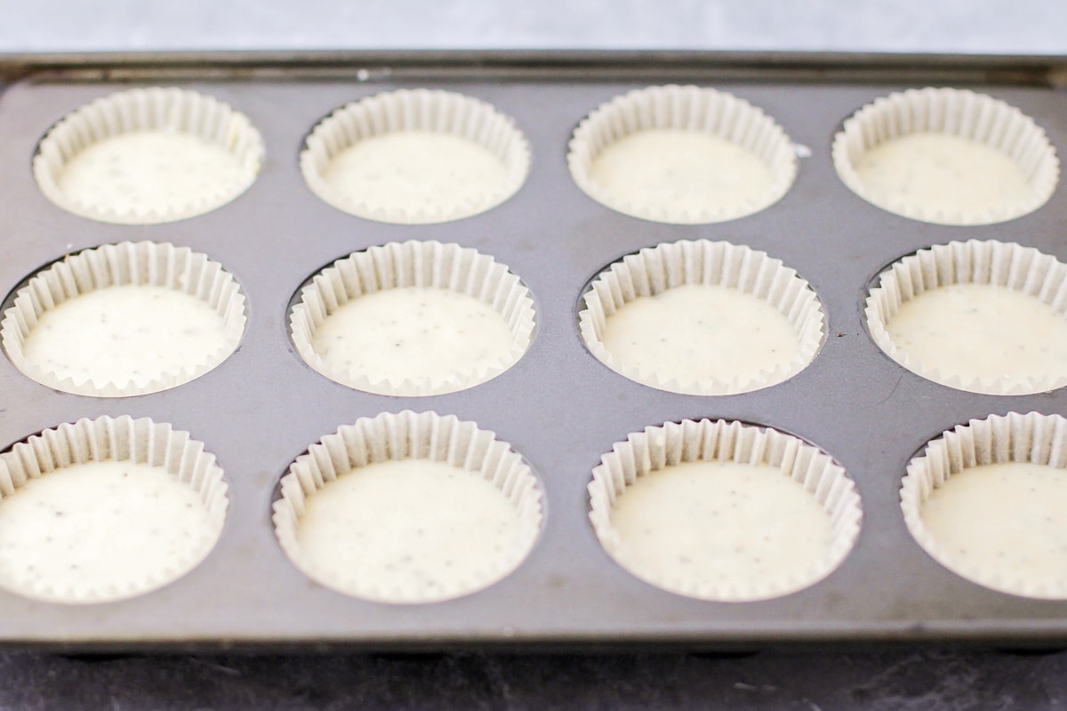 杏仁罂粟籽松饼面糊放在纸杯蛋糕衬里准备烘烤。