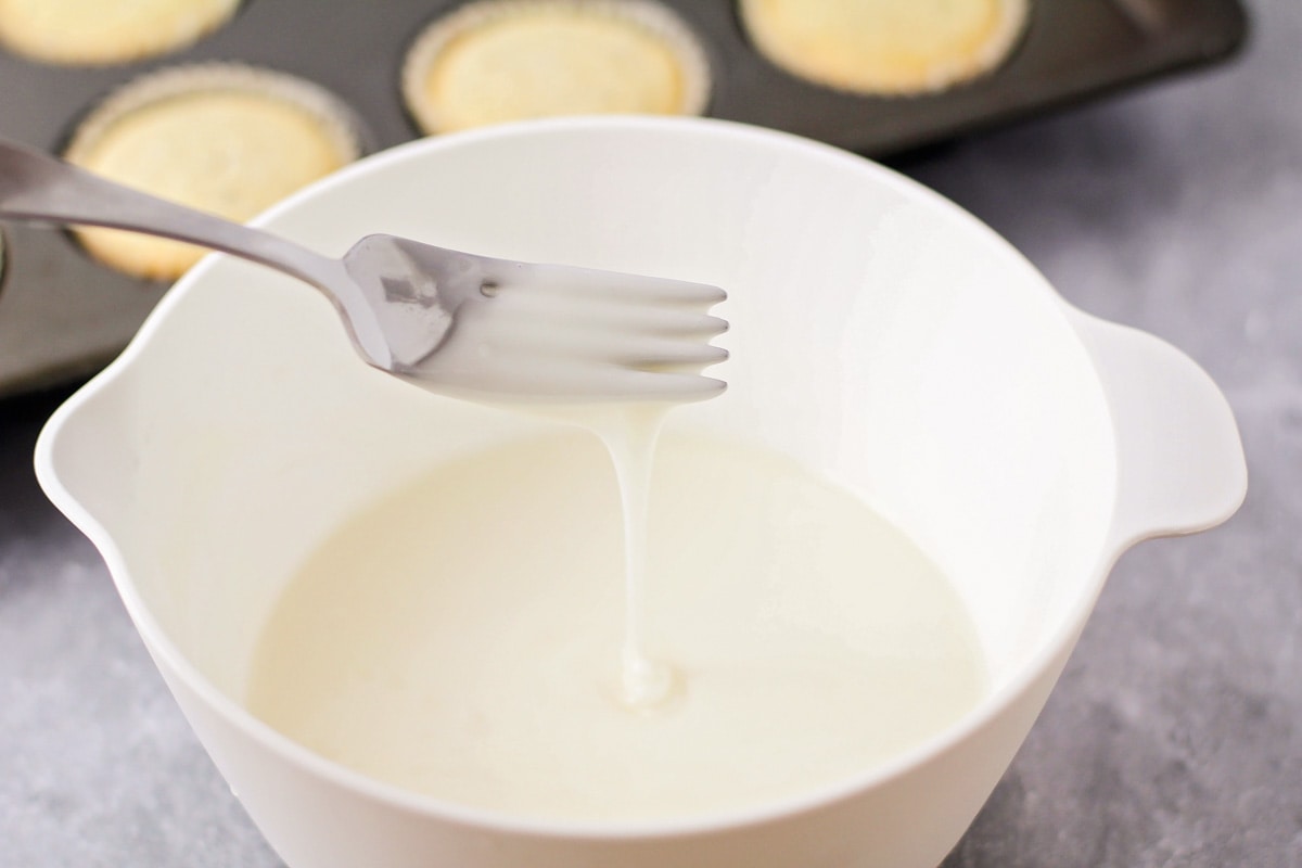 在一个白色的碗里混合杏仁罂粟籽松饼的釉料。
