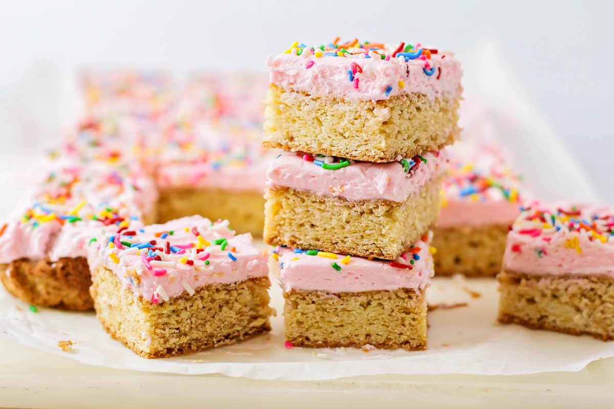甜点条食谱-白色盘子上有bob综合手机客户粉色糖霜和彩虹糖屑的糖饼干条。