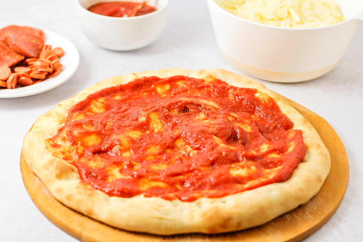在自制的意大利辣香肠披萨面团中加入酱汁。