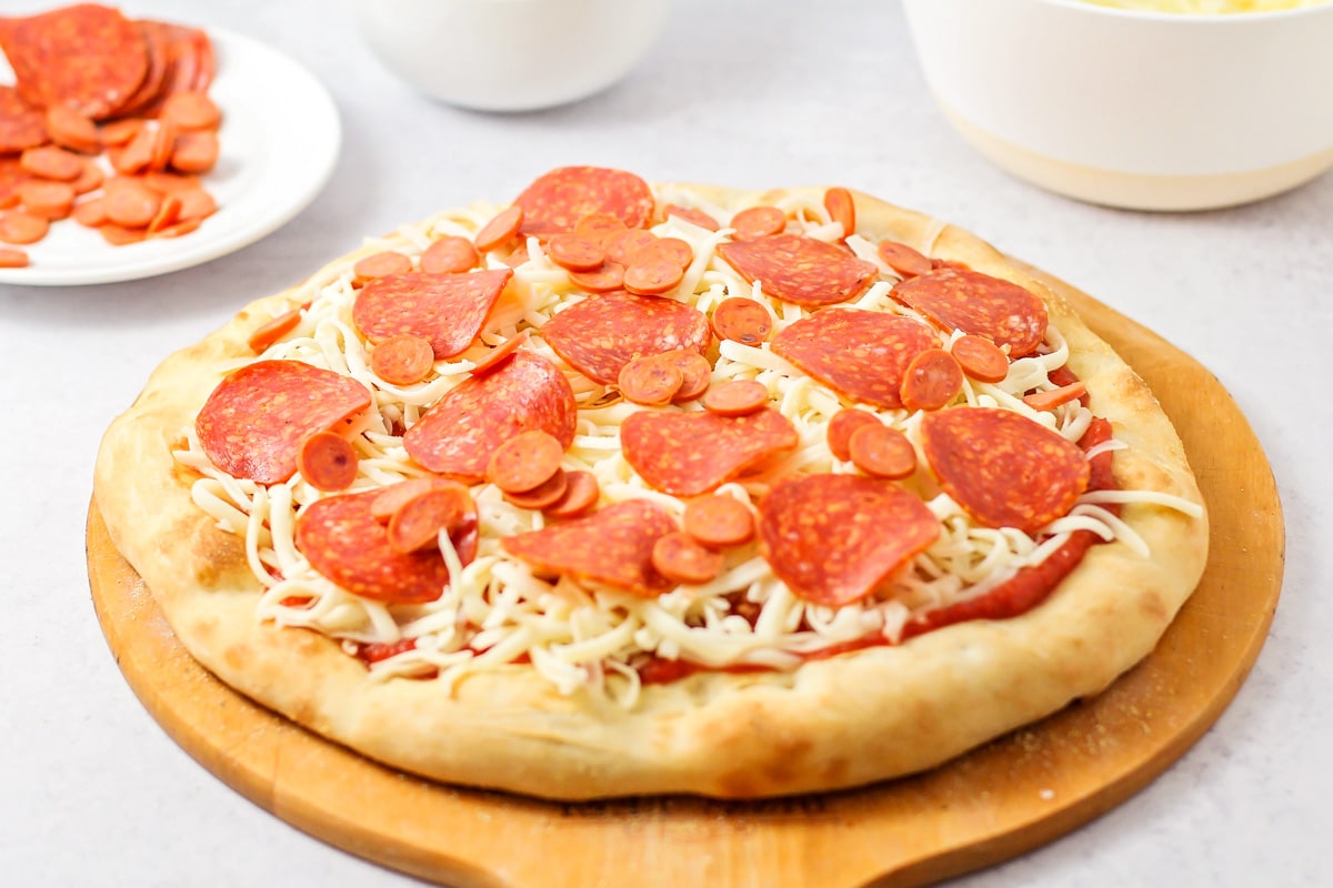 在自制的意大利辣香肠披萨面团中加入奶酪和意大利辣香肠。