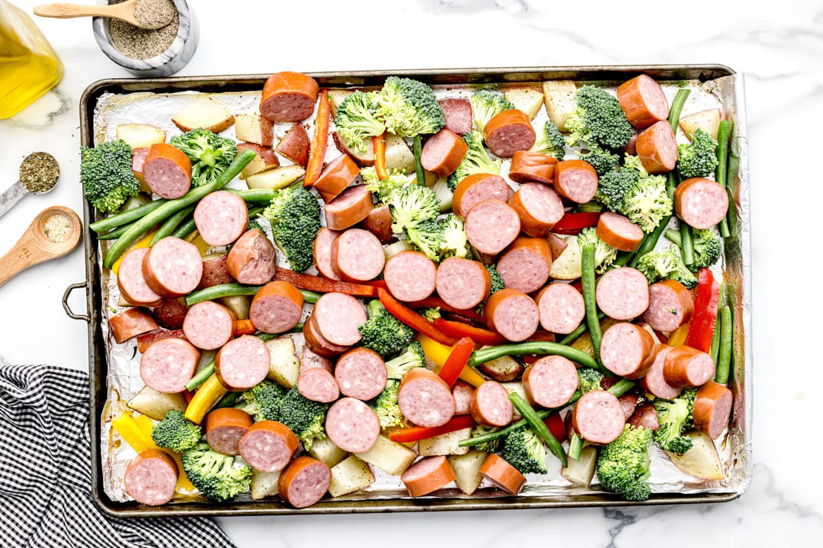 将香肠和蔬菜放在烤盘上准备烘烤。
