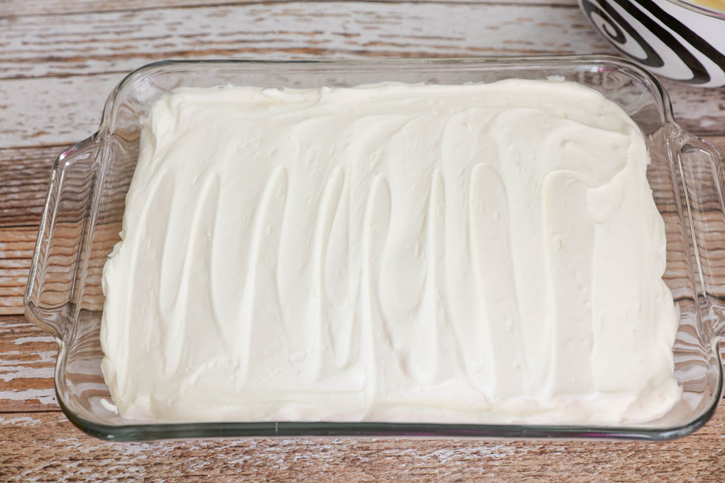 在一个9x13的平底锅中放入复活节泥蛋糕，将奶油层抹平。