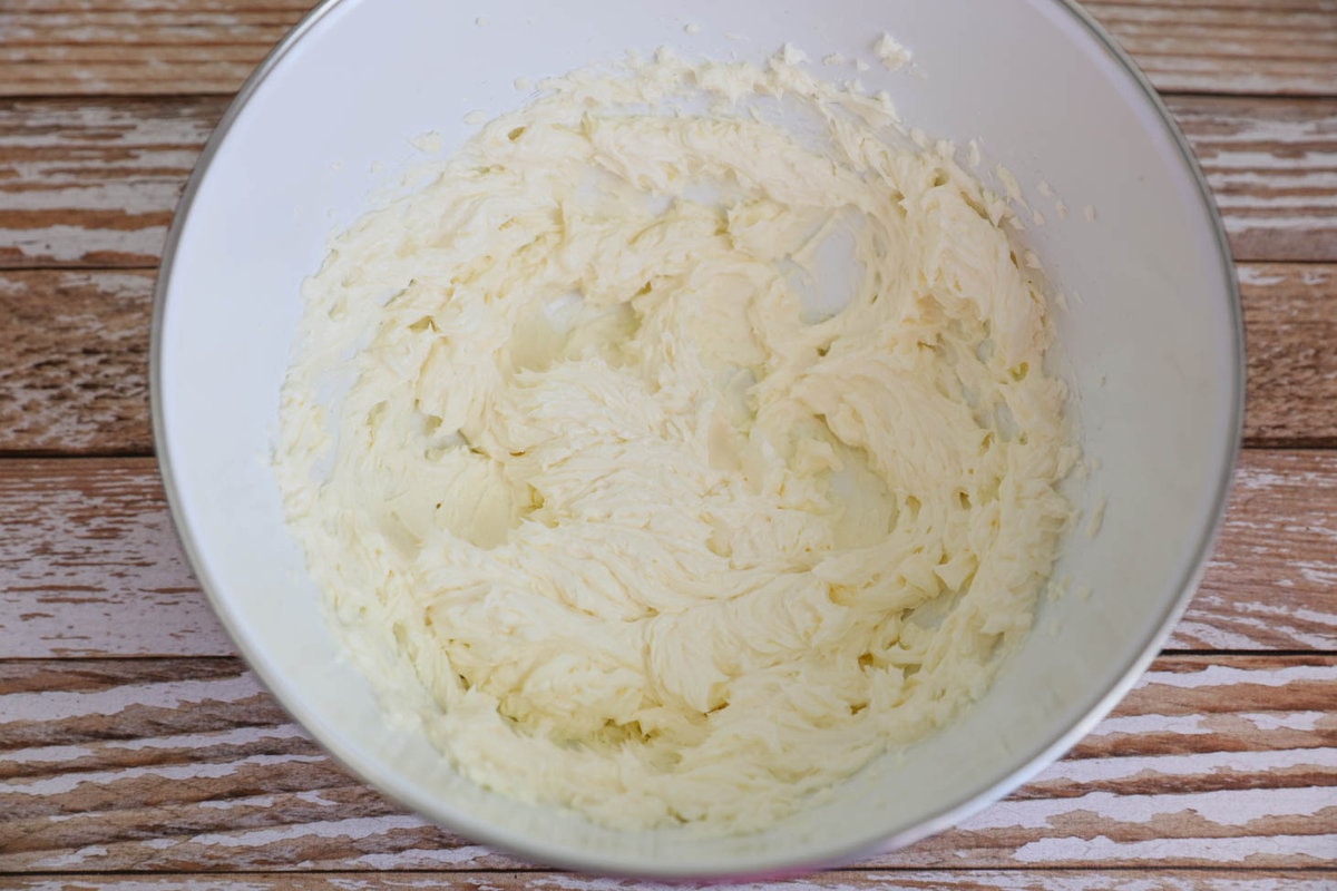 奶油奶酪和黄油混合在一个白色的搅拌碗里。